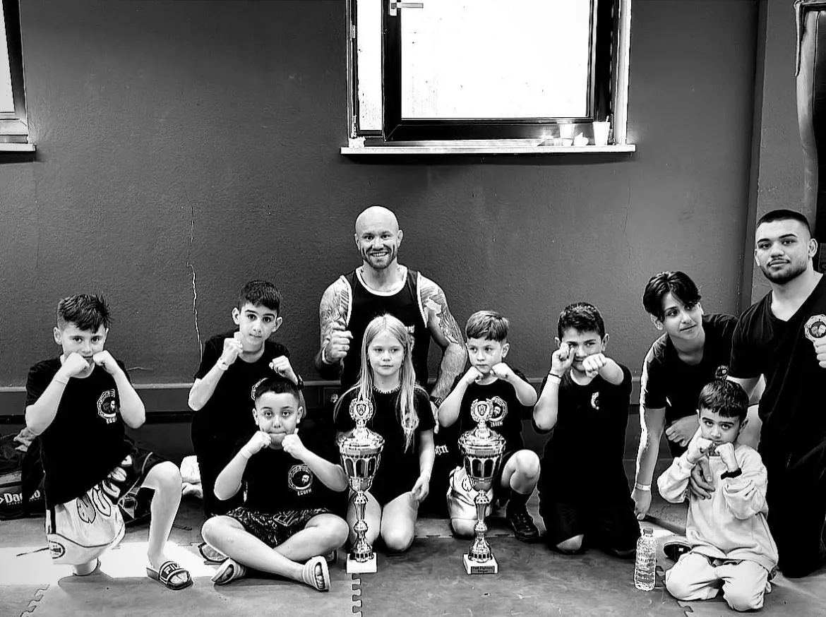Kindergruppe von Comeback Sports mit Boxhandschuhen, Pokalen und Trainer